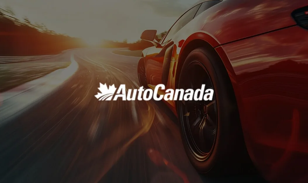 Red sports car driving on highway at sunset with AutoCanada logo overlay, representing a top Canadian automotive group.