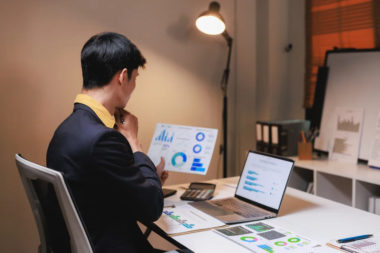 Automotive marketer reviewing digital advertising analytics reports at a desk