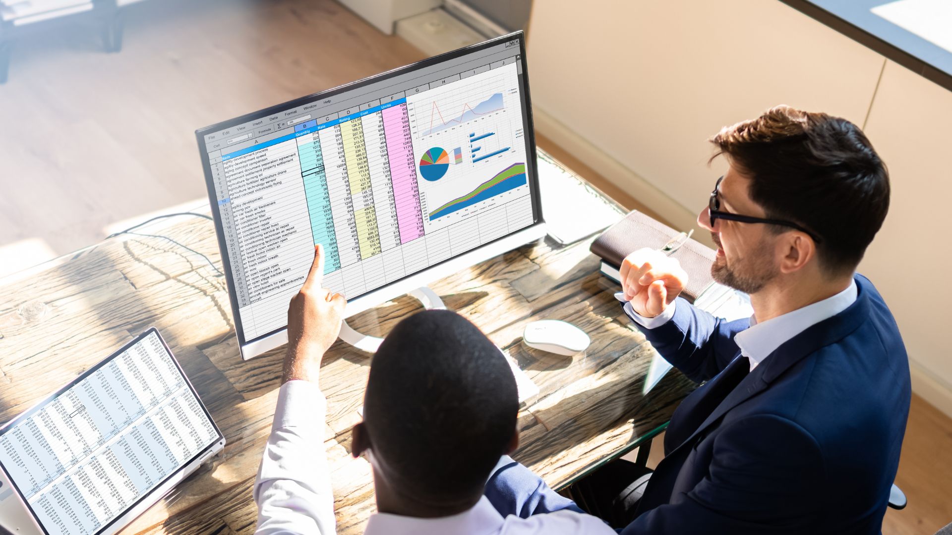 Two marketers reviewing GA4 campaign tracking audit data on a spreadsheet with charts and graphs.